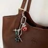 Brown leather handbag strap featuring a silver chain with red and green dice charms.