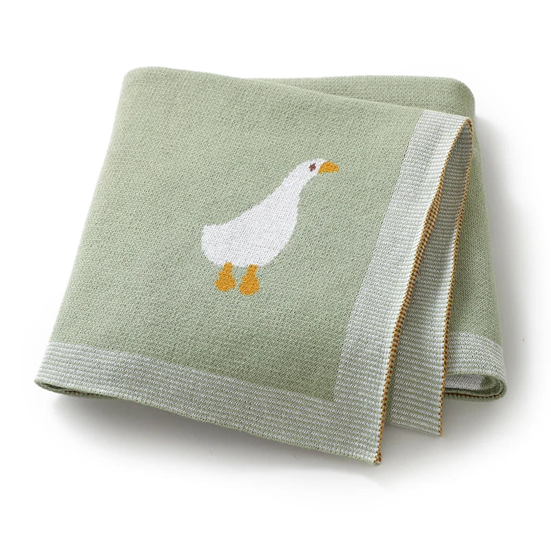 A light green soft cotton baby swaddle blanket featuring a white cartoon duck print.