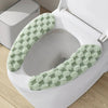 A plush green textured cushion cover for a toilet seat is shown inside a white toilet bowl.