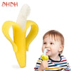 A yellow banana-shaped silicone baby teether and training toothbrush being held by a baby.