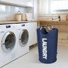 A dark blue foldable laundry bag with padded handles is shown next to a row of white washing machines.