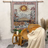 A bohemian jacquard woven throw blanket hangs on a wall, featuring a sun motif and floral designs.