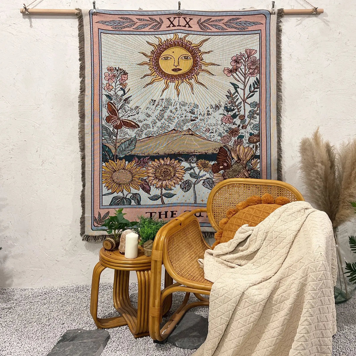 A bohemian jacquard woven throw blanket hangs on a wall, featuring a sun motif and floral designs.