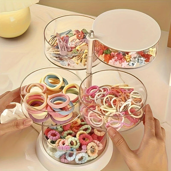 Una mano sostiene un organizador de joyas transparente y giratorio con múltiples niveles de anillos y cuentas de colores.
