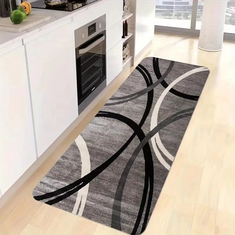 A rectangular gray and white geometric non-slip rug placed on a light wood floor next to kitchen cabinets.