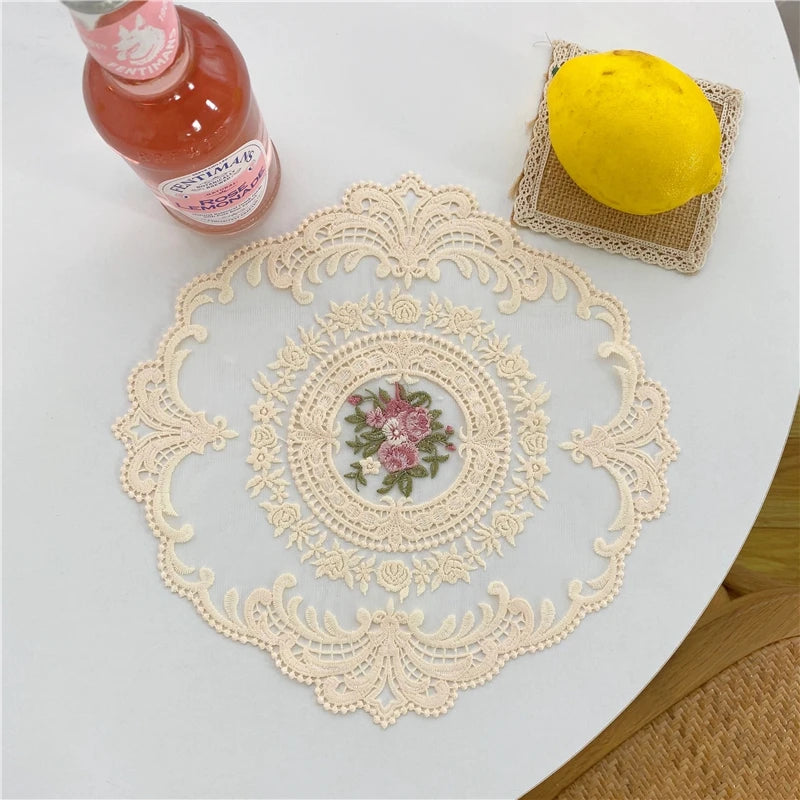 Elegant oval lace embroidered placemat with a yellow lemon and a glass bottle on a white table.