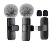 A black USB-C wireless lavalier microphone with a fuzzy windscreen and various attachments shown on a white background.