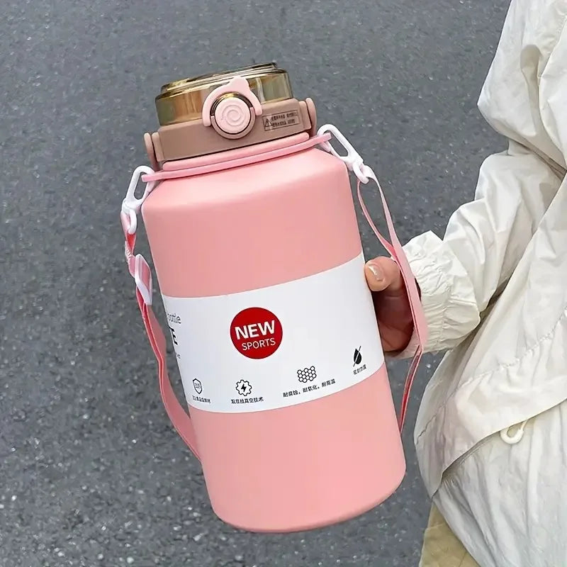 A pink insulated stainless steel tumbler with a lid and straw is held by a person against a gray background.