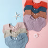 A flat lay of a 3-pack of soft cotton baby bibs in various colors including orange, blue, brown, purple, and green.