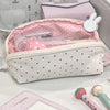 A pink and white polka dot shell-shaped pencil case with multiple compartments is shown on a white surface.