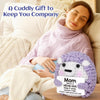 A handmade crochet purple hedgehog doll with an inspirational card resting on a person's lap.