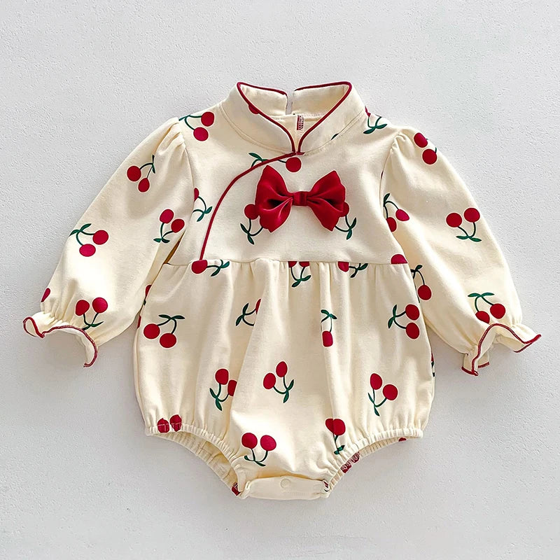 A cream-colored baby girl floral lace cotton romper with long sleeves and a red bow.
