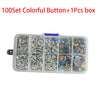 A clear plastic box containing a set of 100 colorful metal buttons for clothing and DIY projects.