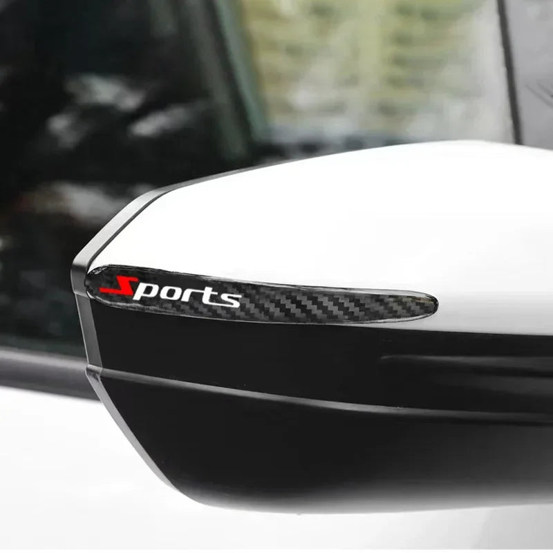 A close-up view of a black car door handle protector featuring a carbon fiber trim and a sports logo.