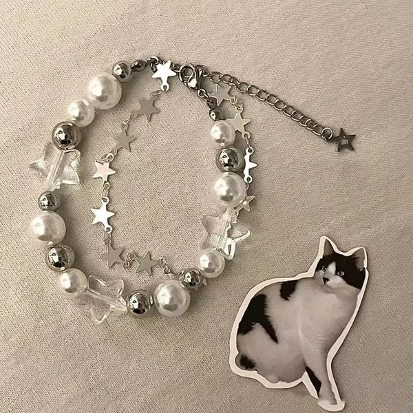 A double-layer bracelet featuring silver chains, star charms, and white pearls, displayed on a neutral background.