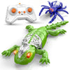 A green wall-climbing gecko toy with silver armor and glowing red LED eyes is shown next to a blue spider and a white remote 