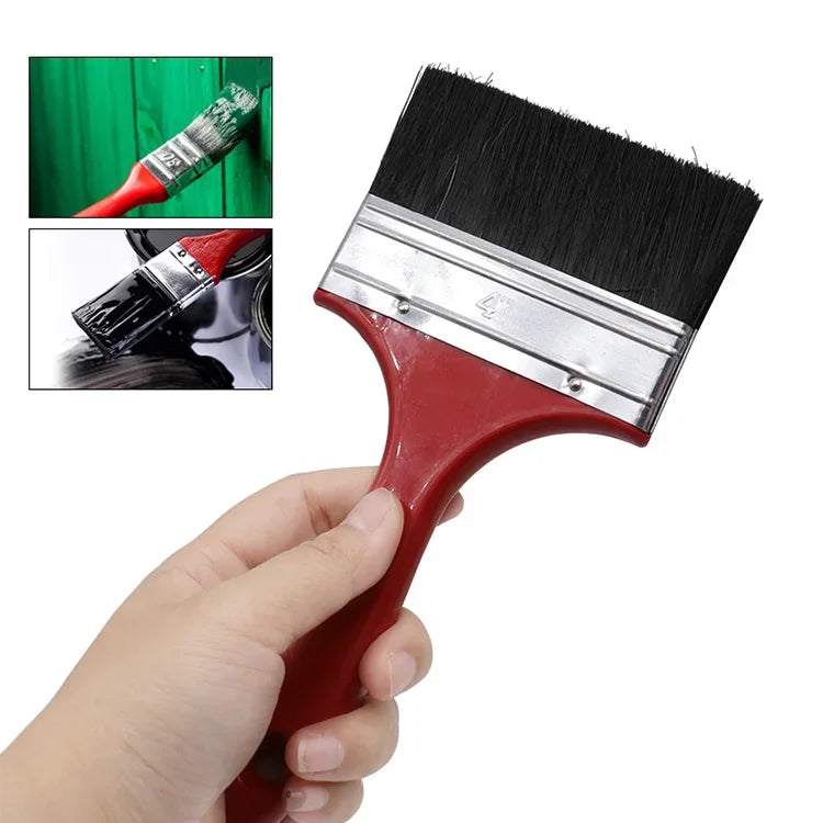 A red paint brush with a black bristled head and plastic handle is shown being held by a hand.