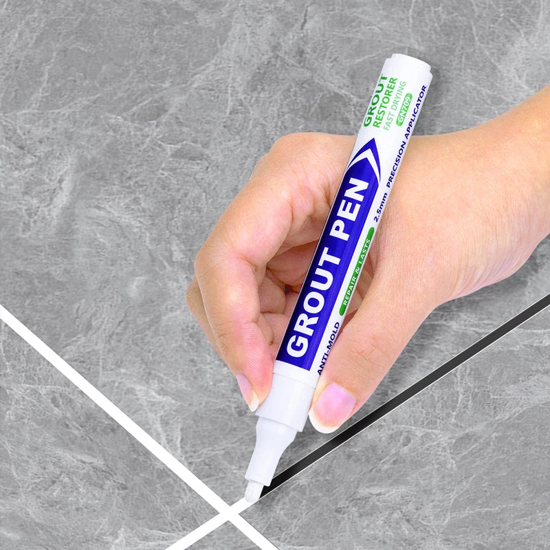 A hand holds a blue grout pen for tile touch-ups against a gray background with white lines.