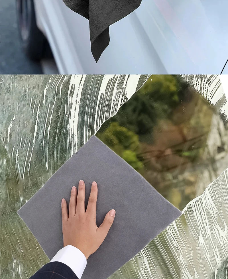A hand holds a gray microfiber cloth against a glass surface, showing the texture of the cloth and a reflection.