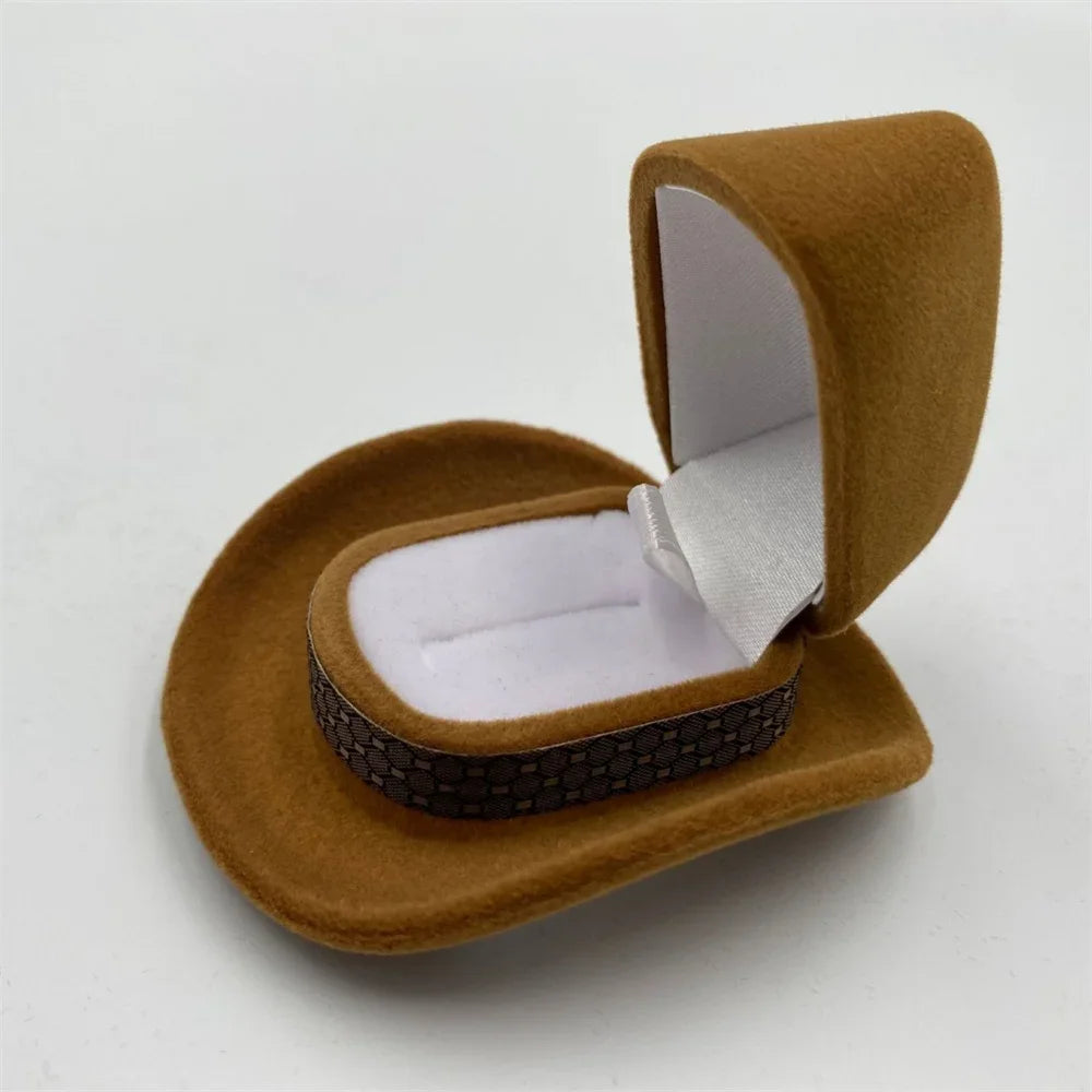 A brown velvet cowboy hat storage box with a secure closure is shown open on a white surface.