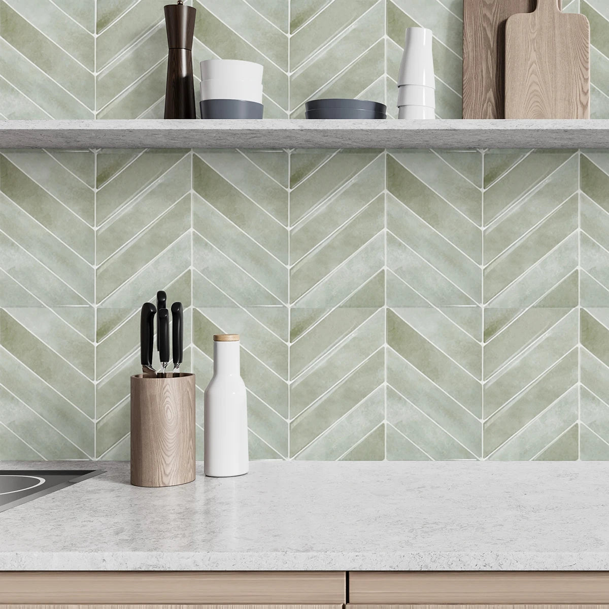 A kitchen shelf displaying various wooden and ceramic kitchen tools against a pale green chevron patterned backsplash.