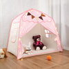 A pink and white teepee play tent decorated with a cutout face design and illuminated by fairy lights.