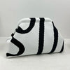 Bolso de crochet trenzado a rayas blancas y negras, visto de lado.
