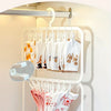 A hand is hanging white and pink t-shirts on a white clip laundry drying rack mounted on a wall.