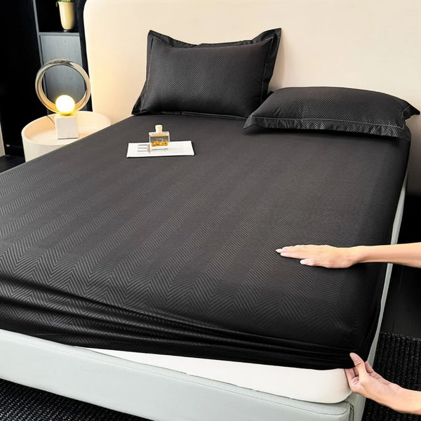 Eine schwarze, eng anliegende Bettdecke liegt auf einem Bett mit Kissen und einer kleinen Lotionflasche daneben.