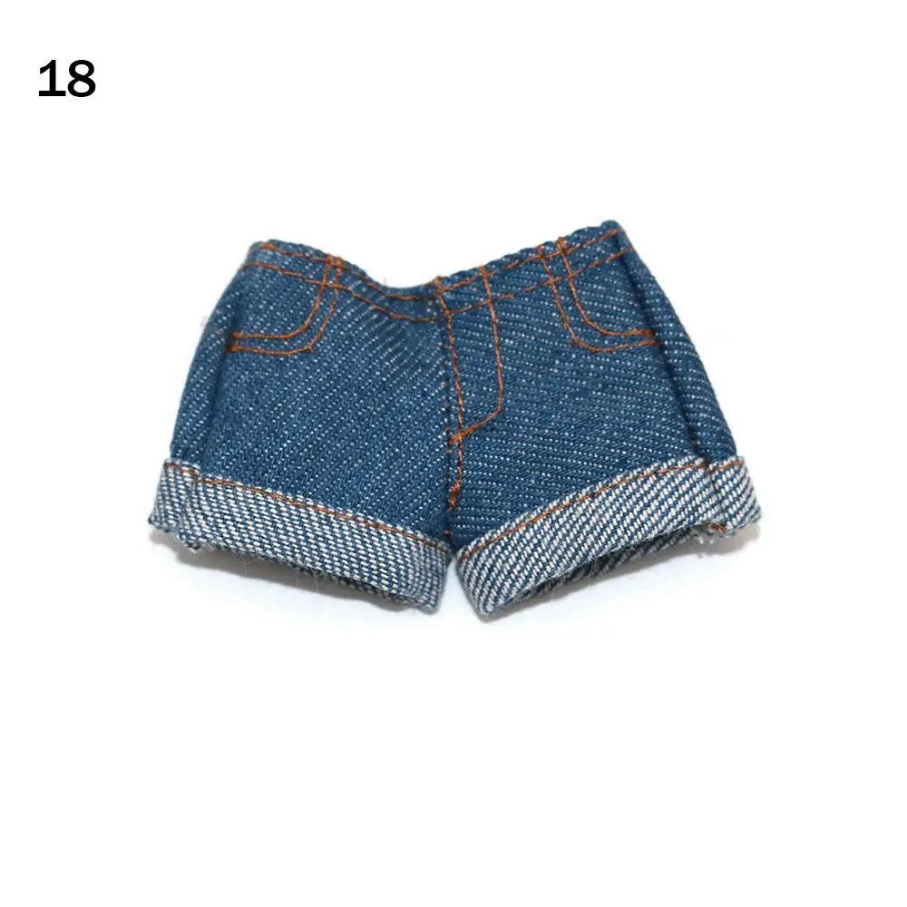 A pair of dark blue denim shorts with orange stitching and a textured hem for fashion dolls.