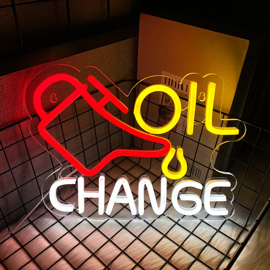 Neon sign displaying the words OIL CHANGE in bright yellow and red on a textured surface.