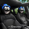 A pair of black car headrest covers featuring creepy smiling face designs on a dark interior seat.