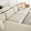 A beige jacquard elastic sofa slipcover with light yellow and orange accent pillows on a white couch.
