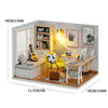 A miniature wooden dollhouse building kit featuring furniture, including a desk, shelves, and a chair.