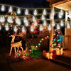 Outdoor holiday lights strung across a yard featuring warm white bulbs and festive greenery.