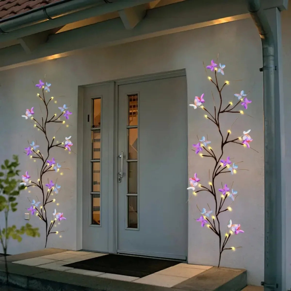 Guirlande lumineuse de vigne de saule avec accents papillon sur une porte et un mur extérieur moderne.