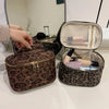 A brown leopard print cosmetic bag with a zippered top and an open interior showing various makeup products.
