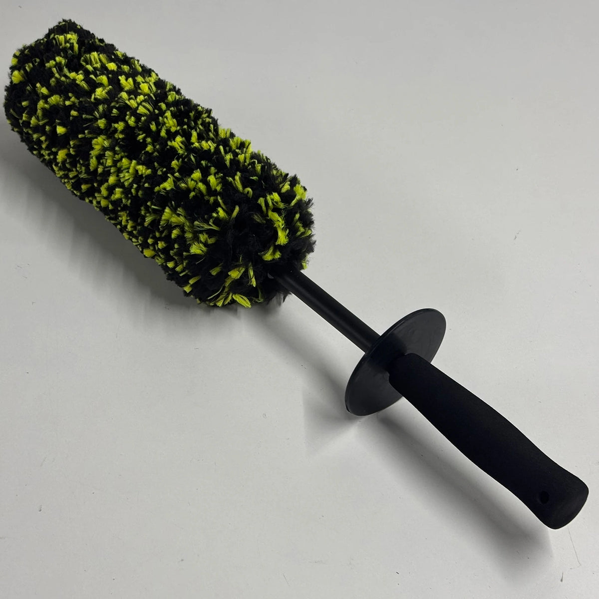 A black wheel barrel brush with a yellow-green bristled head and an ergonomic handle.