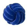 A deep blue velvet throw pillow with a tightly knotted, round design.