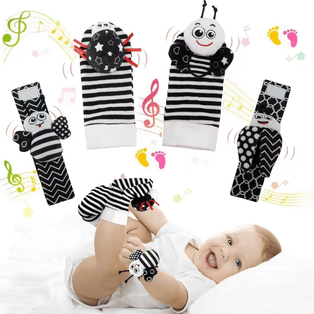 A set of black and white baby rattle socks with sensory toys and a soft teether bootie being worn by a baby.