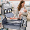 A gray backpack diaper bag with a removable changing mat is shown being held by a woman in a store setting.