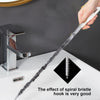 A hand is using a flexible drain cleaning brush with a spiral bristle to clean a sink drain.