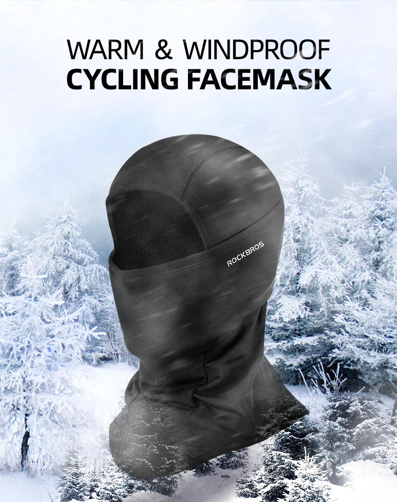 A dark gray cycling facemask is shown against a snowy outdoor background.