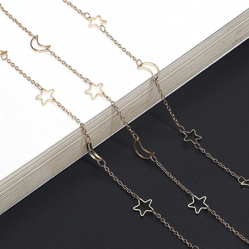 Gold-toned star and crescent moon necklace chain with hollow pendants displayed on a dark background.