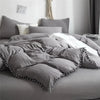 A gray duvet cover set with a pom-pom trim is displayed on a bed.