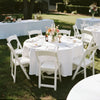 White elegant satin round tablecloth set up outdoors for a wedding or event.