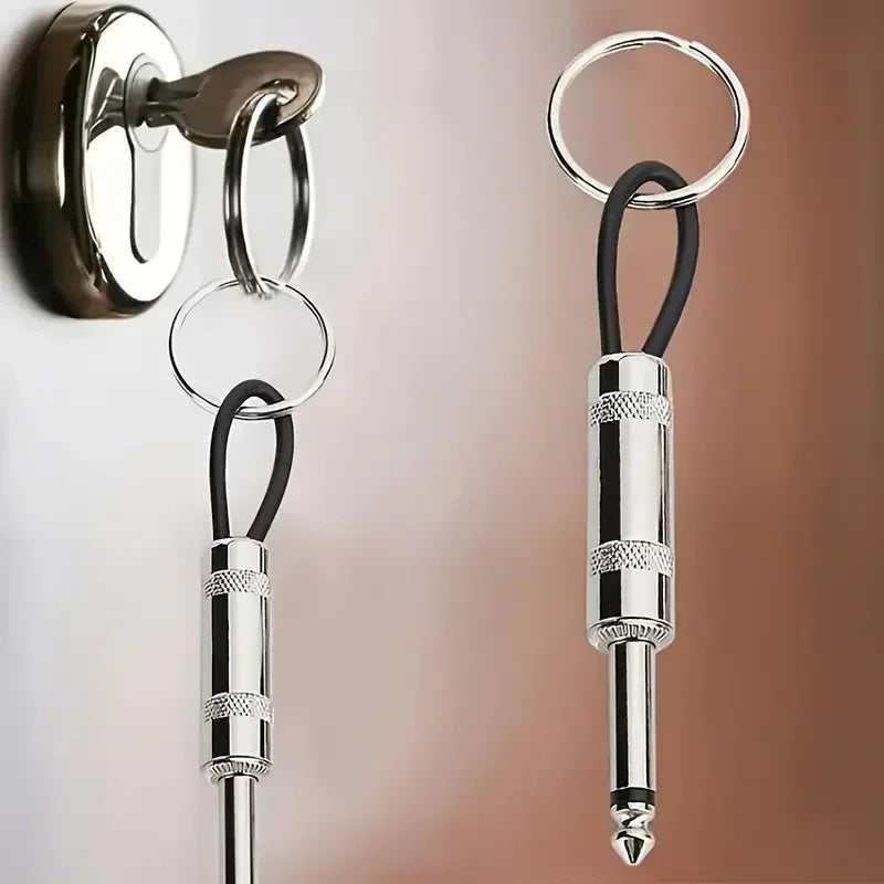 A vintage guitar amplifier wall key holder with a silver and black keyring hanging on a wall.