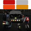 A person is riding a scooter with a reflective strip attached to the rear, near a dark car.