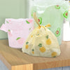 A yellow fruit-print tote bag with handles is displayed next to a large green bag and a pink bag on a wooden surface.