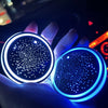 A hand holds a glowing blue LED cup holder light, illuminating the interior of a car.